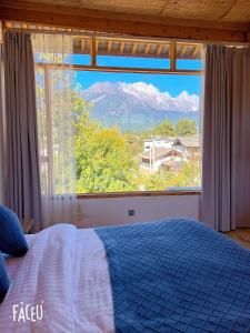 a bedroom with a bed and a large window at Lijiang Shitian B&B in Lijiang