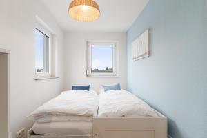 een kleine slaapkamer met een bed en 2 ramen bij Design-Apartment - Küche - Dachterrasse - zentral in Leinfelden-Echterdingen