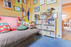 ein Zimmer mit einer Couch und einem Bücherregal mit Büchern in der Unterkunft Le Marine - Maison avec jardin Disney & Paris in Le Perreux-sur-Marne