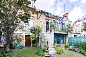 ein Backsteinhaus mit einem Balkon und einem Hof in der Unterkunft Le Marine - Maison avec jardin Disney & Paris in Le Perreux-sur-Marne