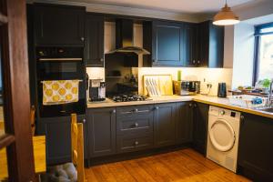 a kitchen with blue cabinets and a stove top oven at 3-bedroom house for outdoor holidays in Alyth