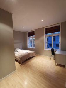 a bedroom with a bed and a desk and two windows at Håkonsgaten 11 in Bergen