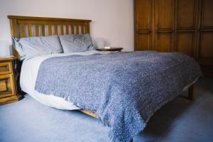 a bedroom with a bed with a blue blanket on it at 3-bedroom house for outdoor holidays in Alyth