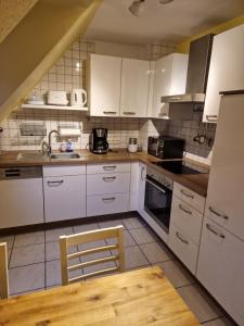 eine Küche mit weißen Schränken und einem Holztisch in der Unterkunft Ruhrpottbude - Private Ferienwohnung im Herzen des Ruhrgebiets in Bochum