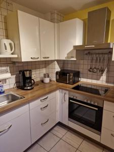 een keuken met witte kasten en een fornuis met oven bij Ruhrpottbude - Private Ferienwohnung im Herzen des Ruhrgebiets in Bochum