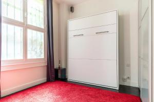 Armario blanco con alfombra roja y ventana en Studio sur les quais de Seine en París