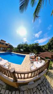 una piscina con sedie a sdraio e un resort di Diver Village Ilhabela a Ilhabela