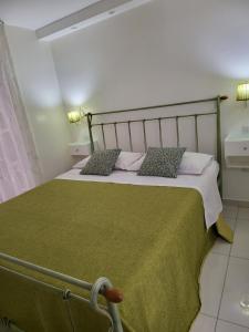 a bedroom with a bed with a green blanket and pillows at MEGARA HOUSE in Naples