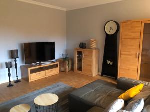 a living room with a couch and a clock on the wall at Gemütliches Apartment Garden View in Ramstein-Miesenbach