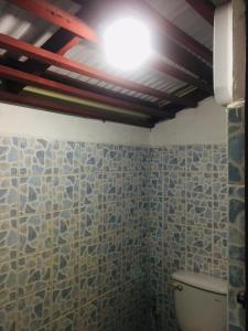 La salle de bains est pourvue de toilettes et d'une lumière au plafond. dans l'établissement Racha Sunset Resort, à Siboya