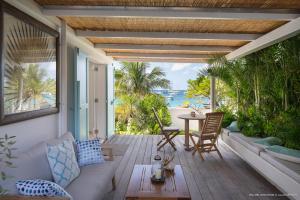 a porch with a couch and a table with a view of the ocean at On the Beach , in Saint Barth... Mellow Mood Villa in Saint Barthelemy