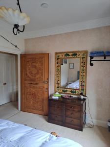 ein Schlafzimmer mit einem Spiegel, einer Kommode und einem Bett in der Unterkunft Lloyds Penthouse in Tavistock