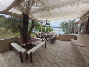 a patio with a table and chairs and a tree at Beach House Onar in Diaporos