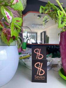 un cartel en una mesa junto a un jarrón con plantas en Seven boutique hotel en Sestri Levante