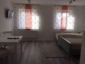 1 dormitorio con 2 ventanas, 1 cama y 1 mesa en Apartmentvermietung Ingrid Bolkart - Kirchblick 1, en Illertissen