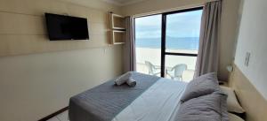 1 dormitorio con 1 cama, TV y ventana en Bellmare Florianópolis, en Florianópolis