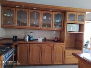 a kitchen with wooden cabinets with glass doors at Preciosa Parcela en Calera de Tango in Santiago