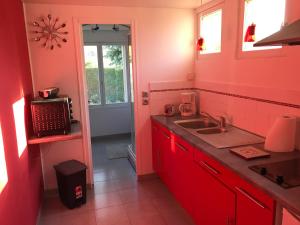 Una cocina roja con un fregadero y una ventana. en Gîte indépendant Diz'enreves au cœur des vignes, en Dizy 8 fotos más