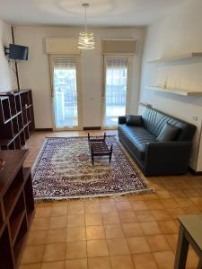 a living room with a black couch and a rug at Nic holiday house in Santa Marinella