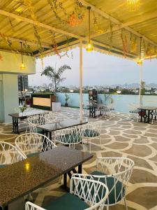 a patio with tables and chairs and a view of the water at Hotel LAAKHAN BY GHUMO UDAIPUR in Udaipur