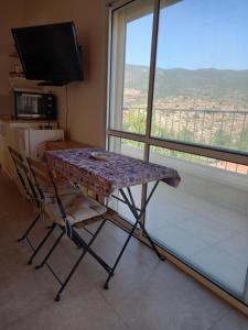 uma mesa e cadeira num quarto com uma grande janela em צימר דביר em Kefar H̱ananya