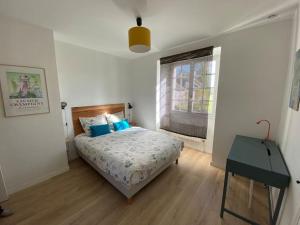 Un dormitorio con una cama con almohadas azules y una ventana en Gîte de la Madeleine 3*, proche de la Loire, en Gennes
