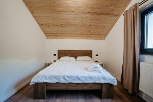 a bedroom with a bed with a wooden ceiling at Green Garden in Borşa