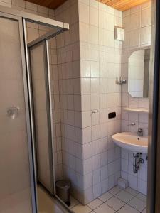 W wyłożonej białymi kafelkami łazience znajduje się umywalka i prysznic. w obiekcie Einzel Zi Nr 2 w mieście Freiensteinau
