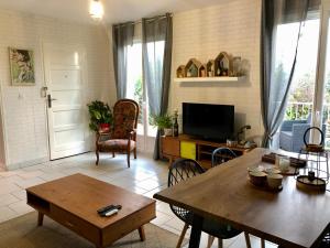 ein Wohnzimmer mit einem Tisch und einem TV in der Unterkunft Comme à la maison in Marsan