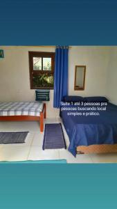 a room with two beds and a window with blue curtains at SUITES E CHALES PRIVADOS Rock's&Rose's home in Camburi