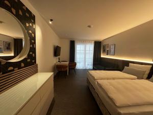 Habitación de hotel con 2 camas y espejo en GreenLeaf Regensburg I Sinzing, en Sinzing