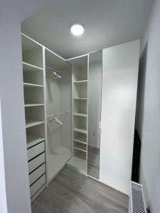 a walk in closet with white shelves and a mirror at Arini Cozy Corner in Şelimbăr