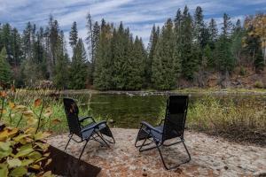 萊文沃思的住宿－Rivers Edge by NW Comfy Cabins，两把椅子坐在湖边的沙滩上