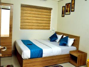 a bedroom with a bed with blue pillows and a window at MARHABA PALACE in Kozhikode