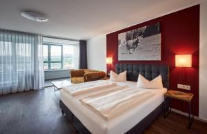 a bedroom with a large bed with a red wall at MY Parkhotel in Kempten