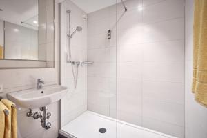 a white bathroom with a shower and a sink at MY Parkhotel in Kempten