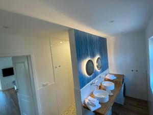 een badkamer met 2 wastafels en een blauwe muur bij Muggelhuus das Ferienhaus im Alten Land / Pflaumenbaum in Twielenfleth