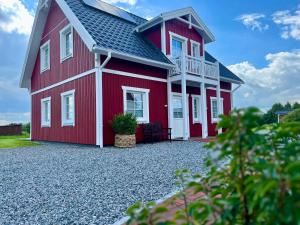 a red house with a balcony on a gravel driveway at Muggelhuus das Ferienhaus im Alten Land / Pflaumenbaum in Twielenfleth