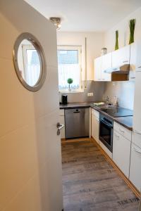 cocina con armarios blancos y puerta con espejo en Art City Studio Kassel 2, en Kassel