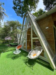 a house with two chairs and a greenhouse at Coffee and Resort in Ko Phayam