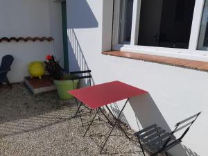 a red table and a chair in front of a building at L'appartement in Le Pradet