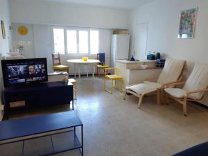 a living room with chairs and a tv and a table at L'appartement in Le Pradet +18 photos