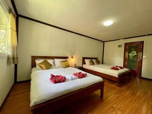 two beds in a room with red towels on them at Khaosok River Camp in Khao Sok National Park