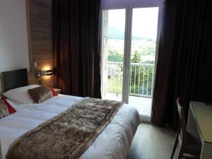 a hotel room with a bed and a large window at Hotel et Résidence Le Clos Cerdan in Mont-Louis