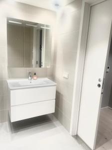 Baño blanco con lavabo y espejo en Seventh Apartment Lillestrøm en Lillestrøm