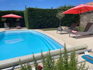 a swimming pool with two chairs and a red umbrella at Le Reve de Breuillac in Surin
