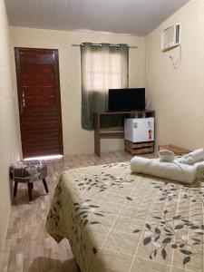 1 dormitorio con 1 cama grande y TV en Pousada Vitória en Pitimbu
