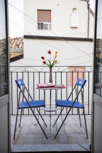 einen Tisch und Stühle auf einem Balkon mit einer Blumenvase in der Unterkunft Sopra La Piazza in Agira