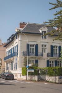 a white house with blue shutters on a street at Hotel Edouard VII in Biarritz