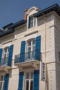 un bâtiment avec des volets bleus et un panneau sur celui-ci dans l'établissement Hotel Edouard VII, à Biarritz